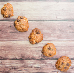 Homemade chocolate chip cookies over weathered wooden surface.