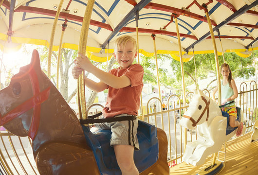Two cute kids having fun while riding a carousel at an amusement park or carnival