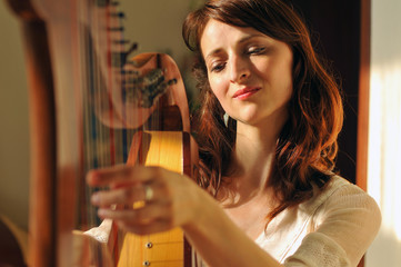 Woman plays celtic harp in folk style