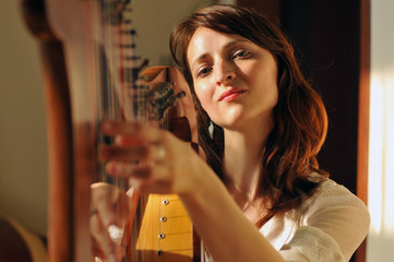 Woman plays celtic harp in folk style