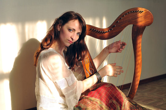 Woman plays celtic harp in folk style