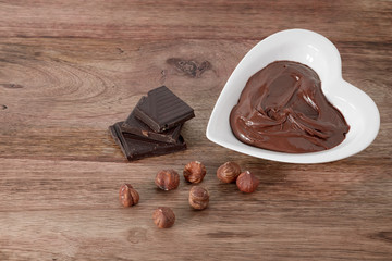 chocolate cream, hazelnut and chocolate on wooden table