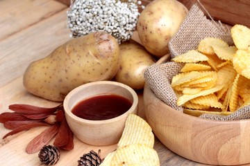 Potato chip and fresh potatoes on wood background