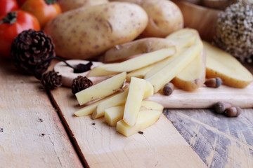 Potato chip and fresh potatoes on wood background
