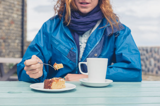 Woman having coffee and cake at table outside