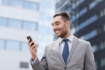 smiling businessman with smartphone outdoors