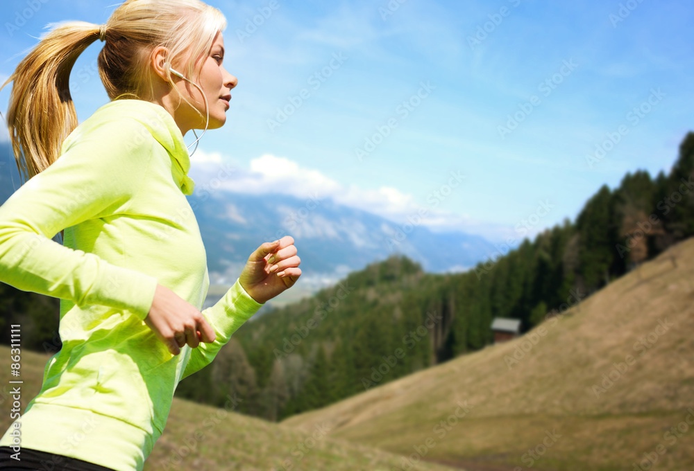 Wall mural happy young woman with earphones jogging outdoors