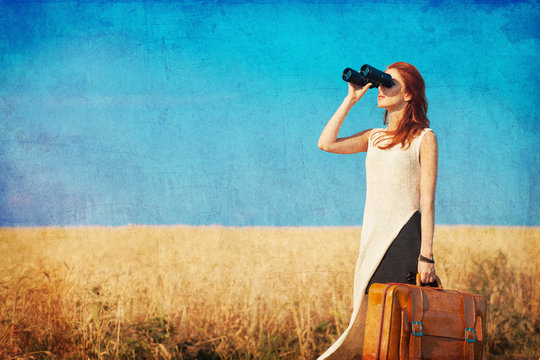 girl with suitcase and binocular at countryside road