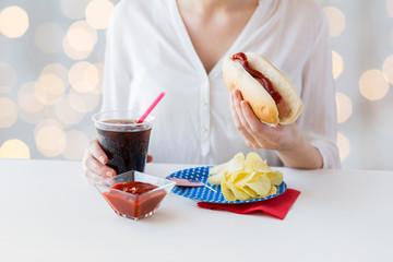 close up of woman eating hot dog with cola