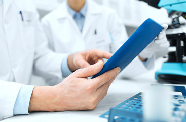 close up of scientists hands with tablet pc in lab