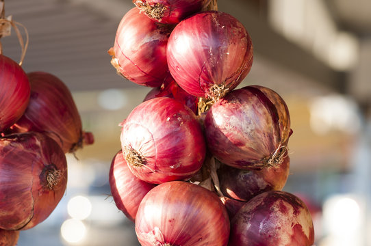 close-up of red onions hanging from a market