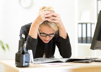thoughtful female worker looking at business papers in office