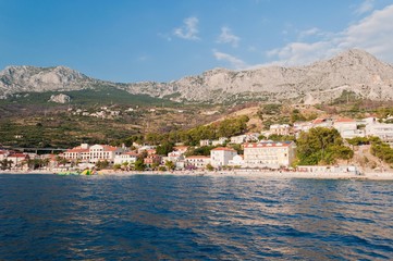 Fototapeta premium Village Podgora with hotels and Biokovo mountain in background. Podgora is a popular holiday resort in Croatia