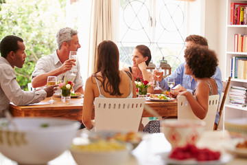 Friends sitting at a table talking during a dinner party