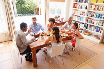 Friends sitting at a table talking during a dinner party