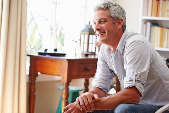 Portrait ofÿa smiling grey haired man sitting in a room