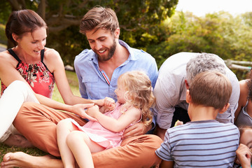 Fototapeta premium Adults and kids sitting on the grass in a garden