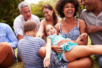Adults and kids sitting on the grass in a garden