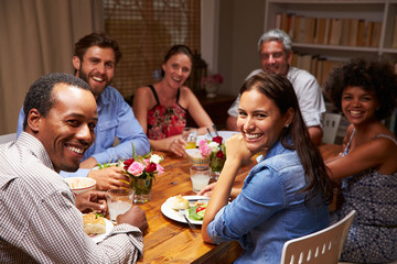 Friends at an evening dinner party, looking at camera