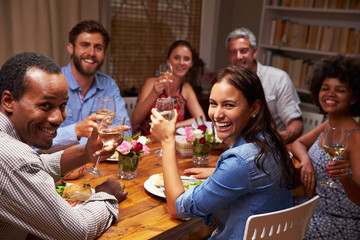 Friends at an evening dinner party, looking at camera