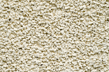 Ecru plaster from pebbles on wall closeup