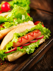 Grilled hot dogs with mustard and ketchup on a picnic wooden table