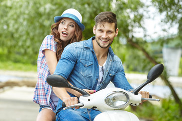 Riding with fun. Beautiful young couple riding scooter together