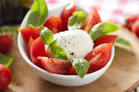 Mozzarella cheese with basil and tomatoes in a bowl