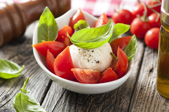 Mozzarella cheese with basil and tomatoes in a bowl