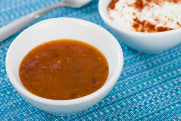 Chilli Dip - Hot chilli sauce in a white bowl on a a blue background.
