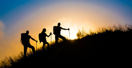 Climbers on grassy hill.
Family three people silhouette walking up steep grassy hill majestic...