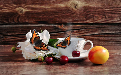 Coffee, cherry, flower and butterfly on a wooden background