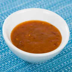 Chilli Dip - Hot chilli sauce in a white bowl on a a blue background.
