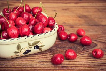Ripe organic homegrown cherries in a vintage ceramic bowl, on wooden background