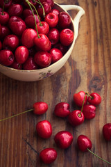 Ripe organic homegrown cherries in a vintage ceramic bowl, on wooden background