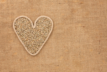 Heart made from rope with rye grains  lying on sackcloth
