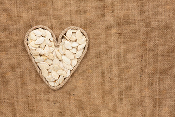 Heart made from rope with pumpkin seeds lying on sackcloth