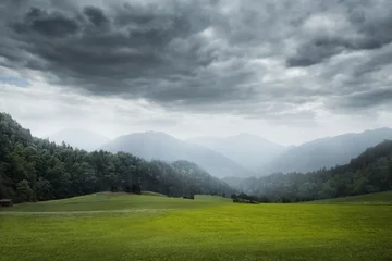 Fotobehang Donkergrijs groene weide en bewolkte lucht
