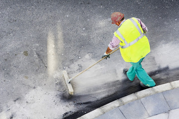 construction worker sweeping with a brush
