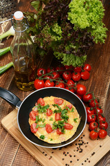 Omelette with ham, tomatoes and chees on the frying pan.
