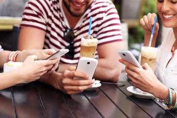 Group of friends in a cafe using smartphones