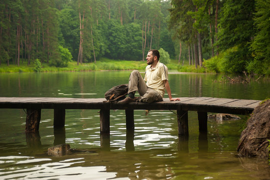 Man Sitting On The Bridge And Look At The Lake