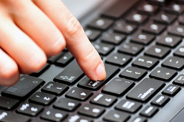 Close up finger pressing enter button on the keyboard