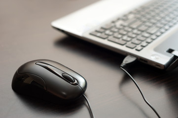 Computer mouse with silver laptop computer on the desk. Image with selective focus