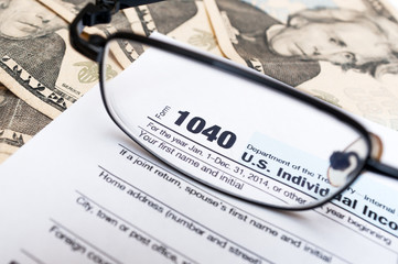 1040 individual tax return form close up, glasses and dollar bills