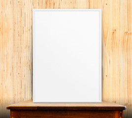 Empty white frame on wooden table at wood wall in background,Moc
