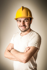 giovane operaio edile sorridente con caschetto giallo protettivo
