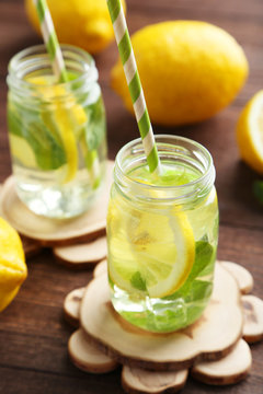 Fresh lemonade with lemon on brown wooden background
