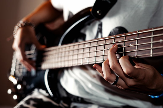 Young adult girl playing five string bass guitar. Color image in horizontal orientation