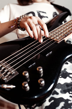 Young adult girl playing five string bass guitar. Color image in horizontal orientation